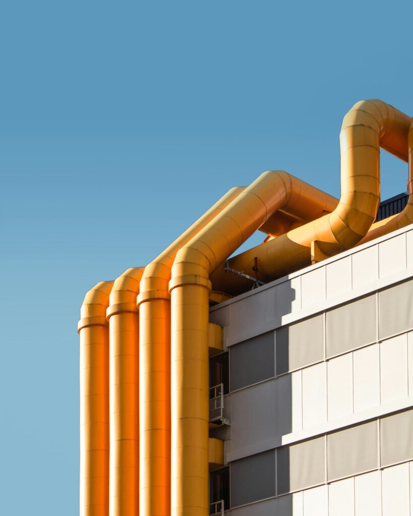 Large yellow process pipework running across an industrial building facade